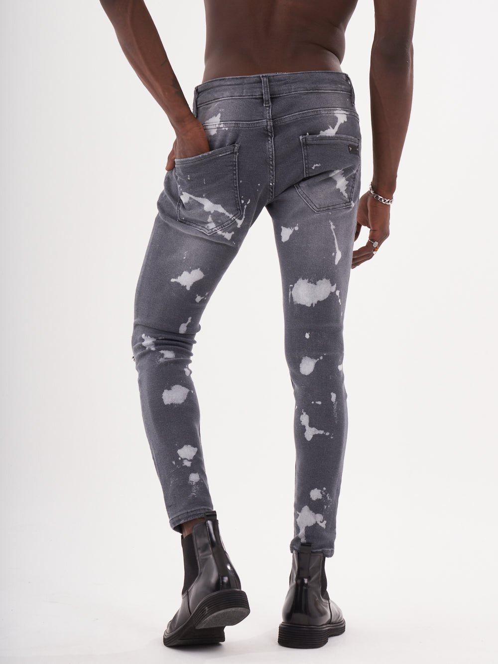 The back of a man in MAVERICK jeans with white paint splatters.