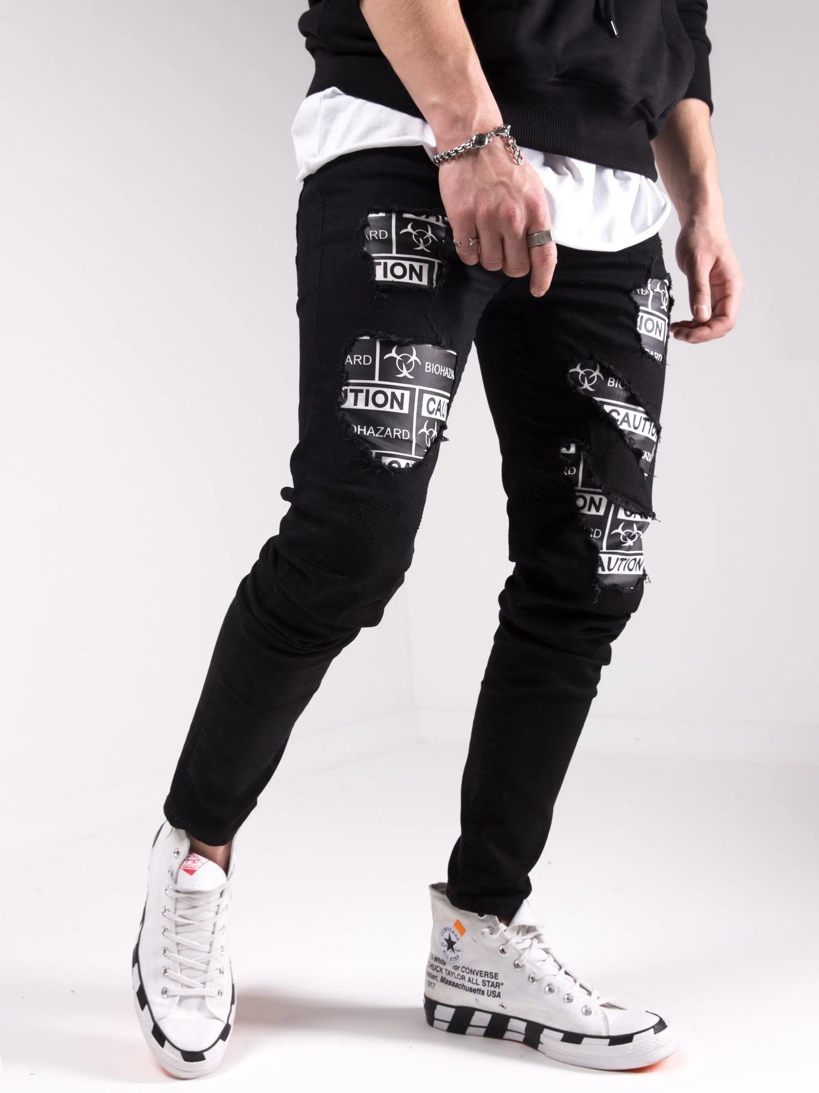 A man wearing BLACKOUT BIOHAZARD jeans and a white t - shirt.