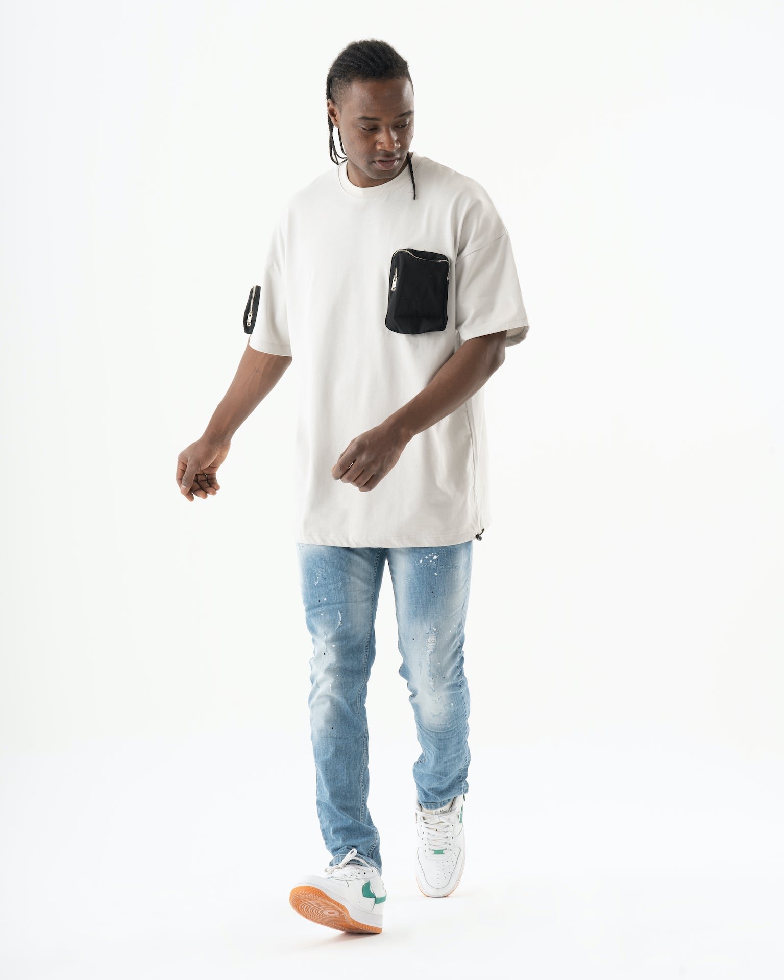 A man in a white t - shirt and jeans walking, wearing skinny fit SKATER jeans.