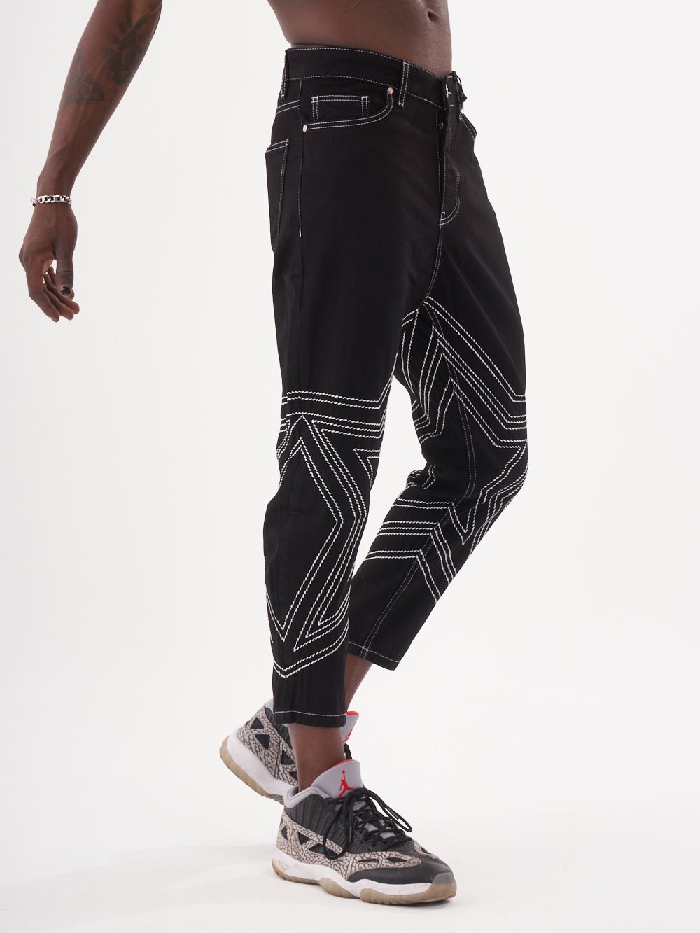 A man wearing a pair of STARDOM jeans and sneakers.