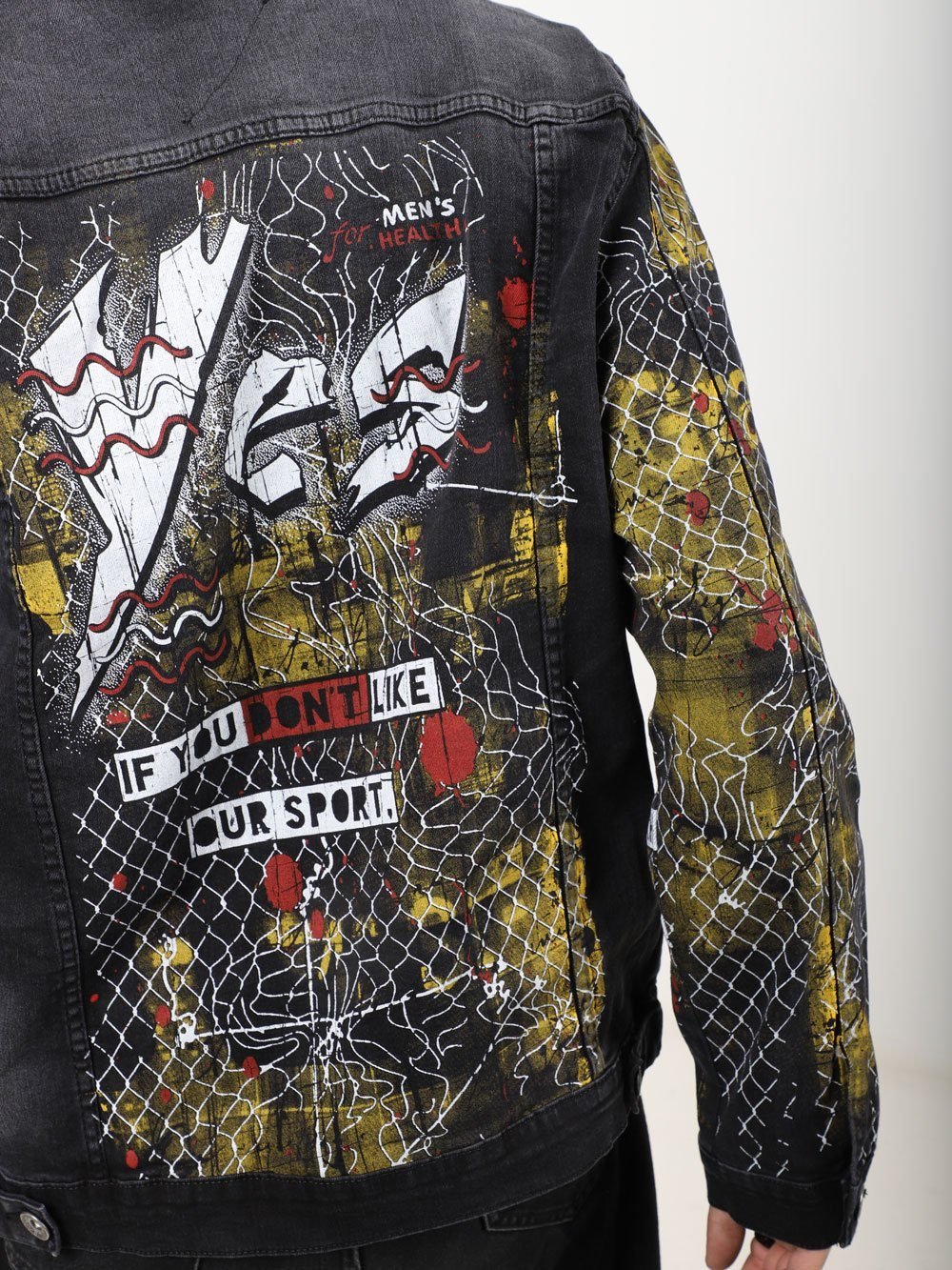 A man wearing a JETMAN denim jacket with graffiti on it.